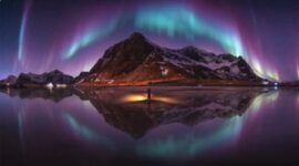 Foto panorama dramatis yang menampilkan Cahaya Utara (Aurora Borealis) membentuk lengkungan langit yang sempurna di atas puncak gunung berselimut salju, karya fotografer asal Bangkok, Wutimet Bunyasirisith, terpilih sebagai pemenang The Pano Awards Southeast Asia Open Photographer of the Year 2026.